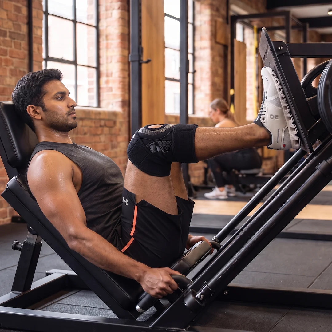 Man doing leg presses wearing an open-patella knee brace